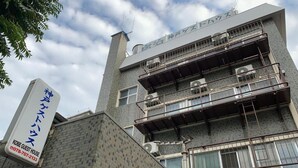 Un edificio de varios pisos con un letrero que indica 'KOBE GUEST HOUSE' y un número de contacto.