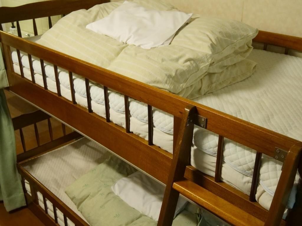 Una cama litera de madera con colchón y almohadas.