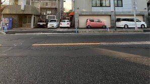 Un edificio de varios pisos con garaje, coches aparcados y líneas eléctricas a la vista.