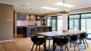 Una cocina moderna con una isla central, taburetes de bar y una mesa de comedor con sillas.
