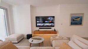 Una sala de estar con un televisor de pantalla plana, un sofá, una mesa de centro y un cuadro en la pared.