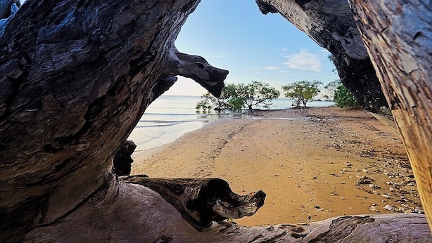 Una formación rocosa natural enmarca una vista de la playa.