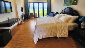 Habitación de hotel con una cama grande, televisión, escritorio y balcón con vistas.