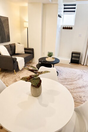 Un salon avec un canapé, une table basse, une plante en pot et une lampe.