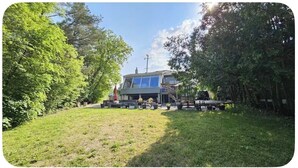 Une maison avec une terrasse, entourée d’arbres.