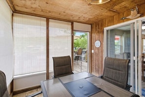 Ein Zimmer mit Holzbalkendecke, zwei Stühlen, einem Tisch und einer Glastür zum Garten.