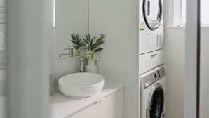 Un bagno moderno con lavandino bianco, specchio e lavatrice integrata.