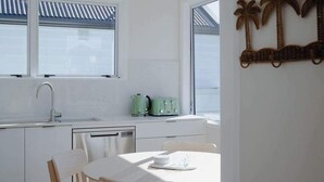Una cucina moderna con mobili bianchi, un tavolo da pranzo con sedie, un'isola centrale e un elemento decorativo a parete.