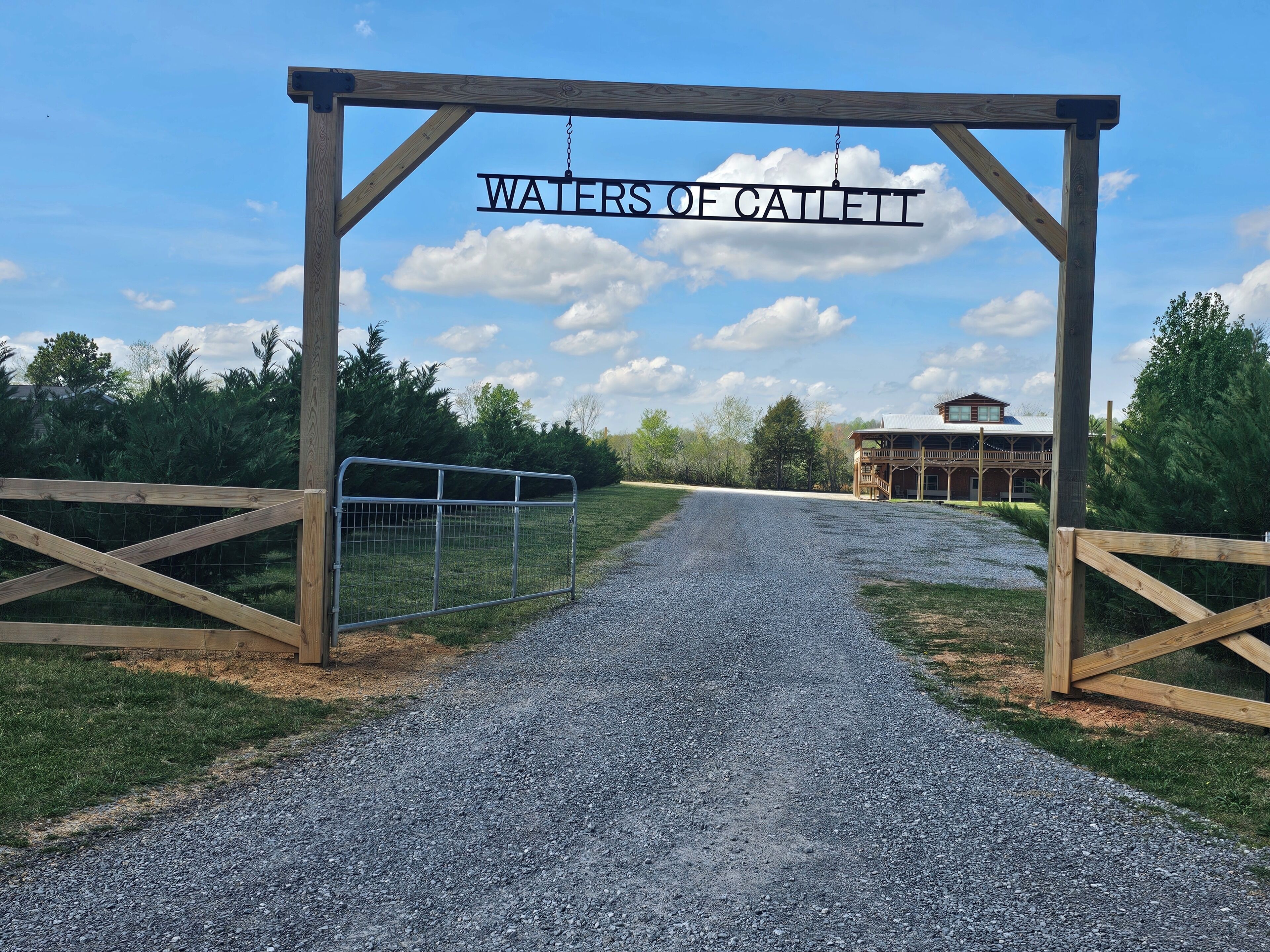 A gravel path leading to a wooden gate with a sign reading 'WATERS OF CAILETT.'
