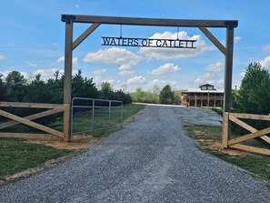Un chemin de gravier mène à une porte en bois sur laquelle est apposée une plaque portant l’inscription « WATERS OF CAILETT ».