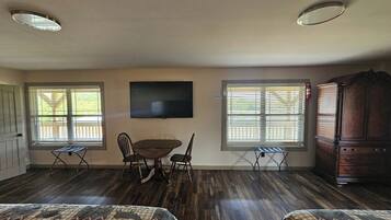 A room with a dining table, two chairs, a TV mounted on the wall, and a wooden cabinet.