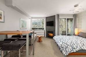 Ein modernes Hotelzimmer mit einem Bett, einem Schreibtisch mit Stühlen, einem Kamin und einem großen Fenster.