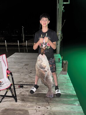 A person holding a large fish on a wooden dock at night. - Enjoyable 2-bedroom house on the intercoastal in charming Sargent, TX (Bay City)