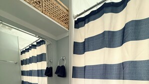 Een badkamer met een gestreept douchegordijn, een wastafel, een spiegel en een handdoekhouder.