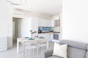 A modern apartment with a dining area, kitchenette, and a living room. - VI residence ° modern apartment +#pool# (Lido di Jesolo)