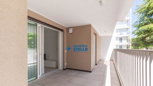 Un corridoio con una porta scorrevole in vetro che dà su un balcone, una parete con il logo 'immobiliare STELLA' e una ringhiera bianca.