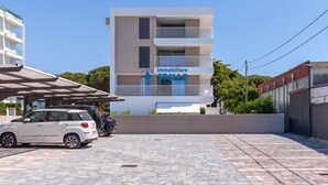 Un edificio moderno con un cartello per 'immobiliare STELLA' e un'area di parcheggio con auto.