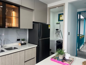 Una cocina moderna con un refrigerador negro, dos lavamanos, un protector contra salpicaduras de mármol y una estantería empotrada para vinos.