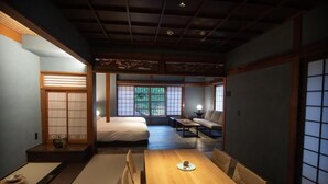 A traditional Japanese-style room with tatami flooring, a low wooden table, and a futon bed.