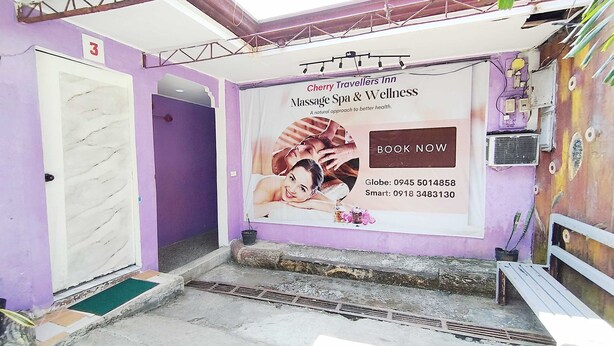 A spa area with a massage service advertisement, a door, and a bench. - OYO 1214 Cherry Travellers Inn (San Jose de Buenavista)