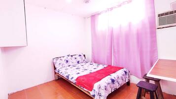 Un dormitorio pequeño con una cama individual, una mesa y una silla.