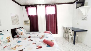 A bedroom with a bed, a desk, a chair, and a window with curtains. - OYO 1214 Cherry Travellers Inn (San Jose de Buenavista)