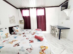 A bedroom with a bed, a desk, a chair, and a window with curtains. - OYO 1214 Cherry Travellers Inn (San Jose de Buenavista)