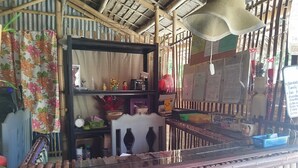 A room with a bamboo ceiling, a glass partition, and various items on shelves including a clock, a vase, and a basket. - OYO 1214 Cherry Travellers Inn (San Jose de Buenavista)