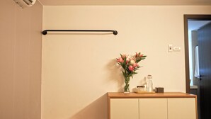 A room with a wooden cabinet, a towel rack, and a vase with flowers. - Private saving room for a solo traveller in Hanoi (Hà Nội)