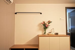 A room with a wooden cabinet, a towel rack, and a vase with flowers. - Private saving room for a solo traveller in Hanoi (Hà Nội)
