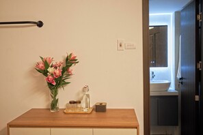 A bathroom with a wooden vanity, a vase of flowers, a glass bottle, and a small tray with items. - Private saving room for a solo traveller in Hanoi (Hà Nội)