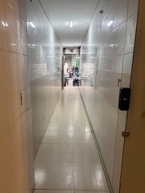 A corridor with tiled walls and a door on the right. - Private saving room for a solo traveller in Hanoi (Hà Nội)