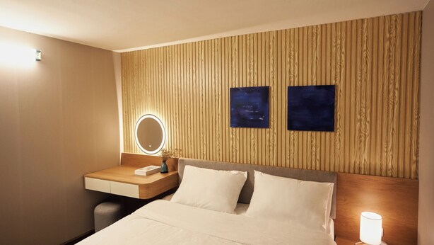 A hotel room with a wooden panel wall, a bed with white bedding, a bedside table with a lamp, and a mirror. - Private saving room for a solo traveller in Hanoi (Hà Nội)