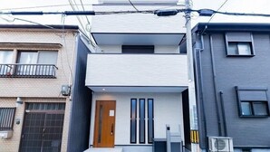 Un immeuble résidentiel moderne à deux étages, doté d’un toit plat, d’une porte d’entrée et d’un petit espace porche.