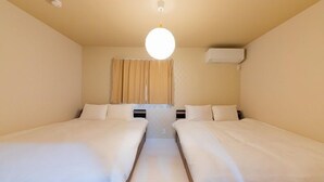 Une chambre avec deux lits, un luminaire au plafond et un appareil de climatisation.
