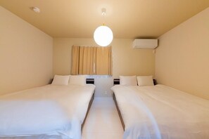 A room with two beds, a ceiling light, and an air conditioning unit. - SUMISORa Osaka (Osaka)