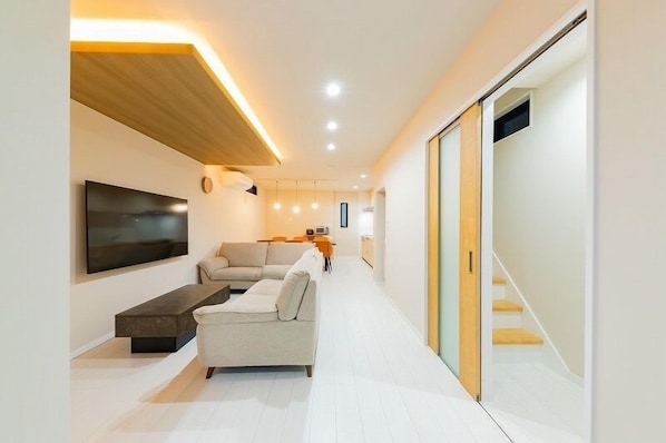 A modern living room with a sofa, a coffee table, and a TV mounted on the wall. - SUMISORa Osaka (Osaka)