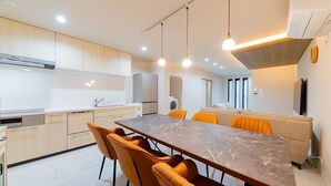 Une cuisine moderne dotée d’un plan de travail en marbre, de meubles en bois et d’un coin repas avec des chaises orange.