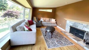 A living room with a fireplace, a sofa, a coffee table, and a rug. - Cross the Street to the Beach & Ocean Views (Victoria)