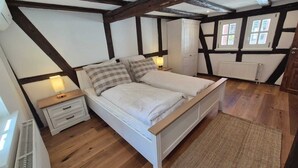 Un dormitorio con cama, mesitas de noche, un radiador y una ventana.