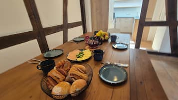 Uma mesa de jantar de madeira com pratos, chávenas e uma taça de pastelaria.