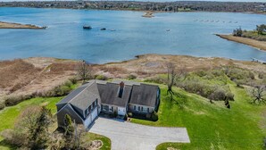 A house with a driveway, a lawn, and a view of a large body of water. - Waterfront Chatham Escape, Pet Friendly, Pond Views & Beach Nearby (Chatham)