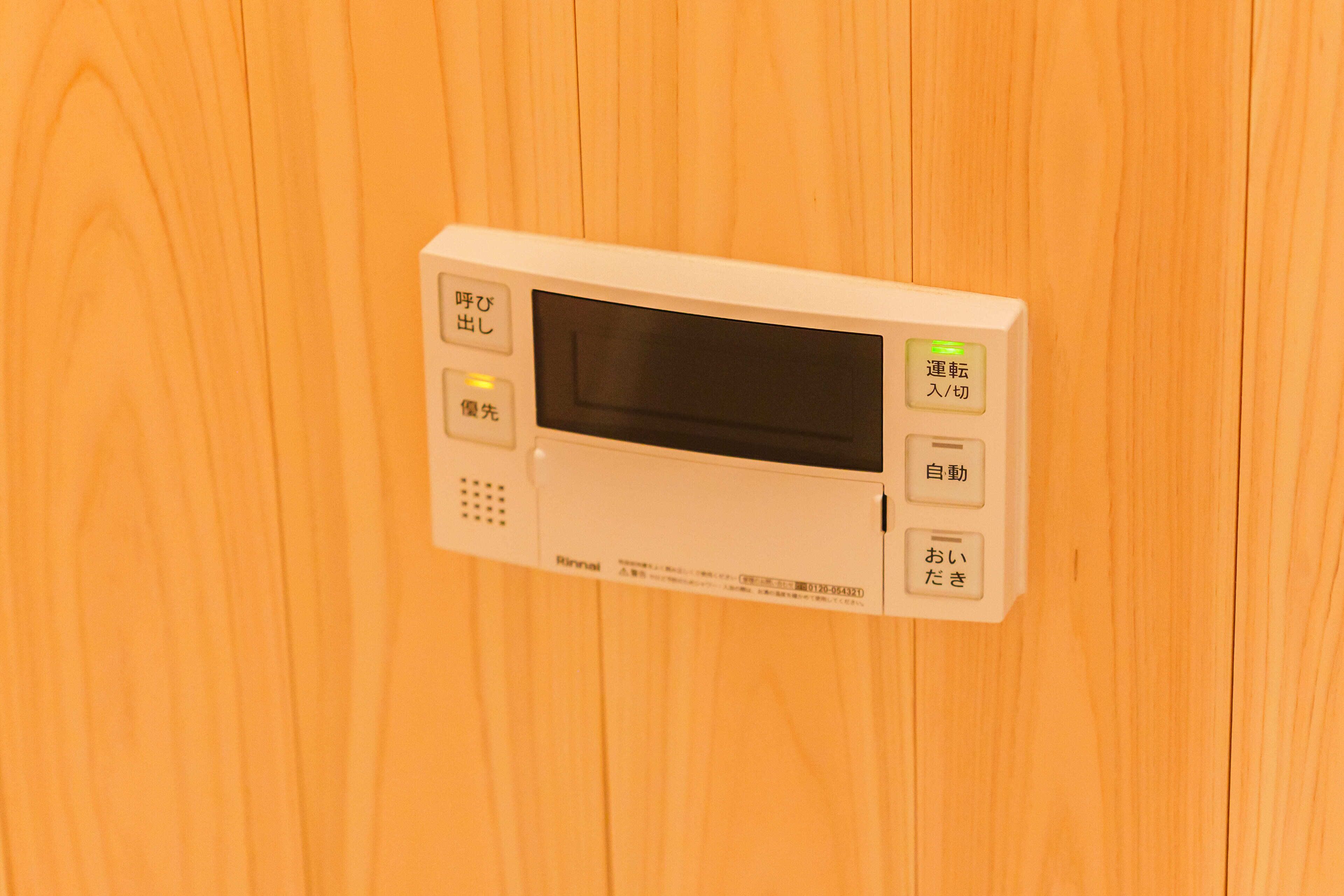 A microwave with buttons and a display, mounted on a wooden wall.