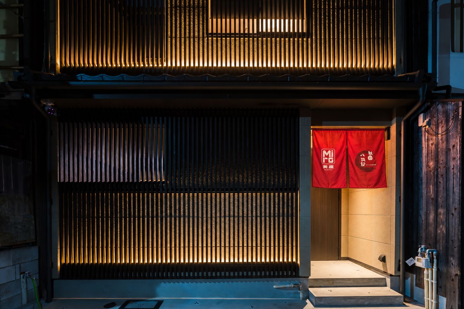 A building with a traditional facade, featuring vertical wooden slats and a red banner with white text.