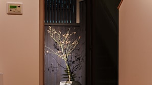 Una puerta que da a una habitación con una planta en maceta y un termostato en la pared.