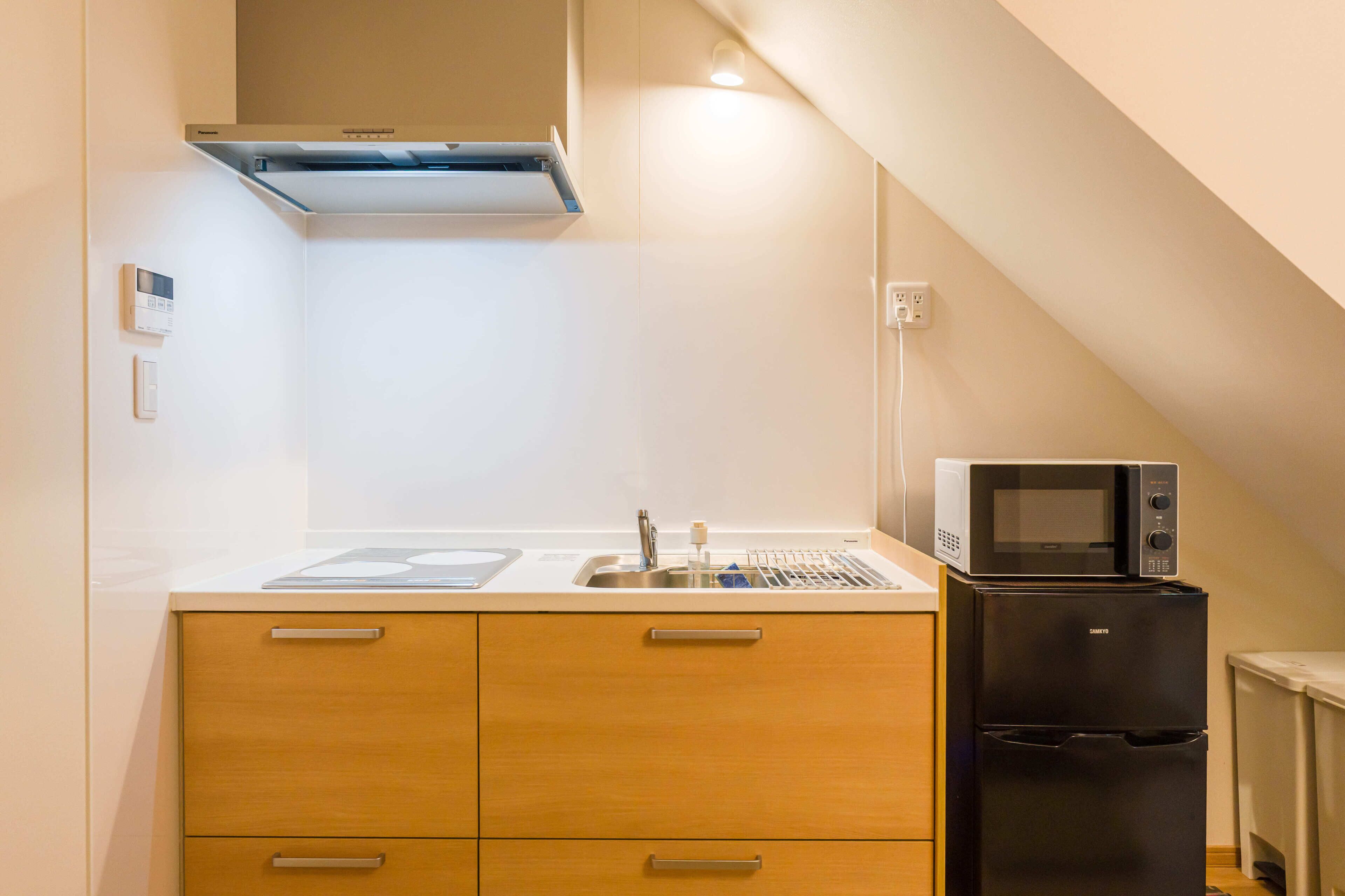 A compact kitchen with a microwave, refrigerator, and a built-in oven.