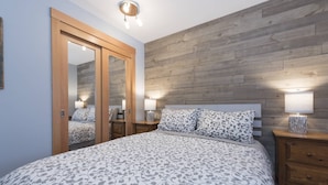 Ein Schlafzimmer mit einem großen Bett, Holzwandverkleidung, einem Spiegel und Nachttischlampen.