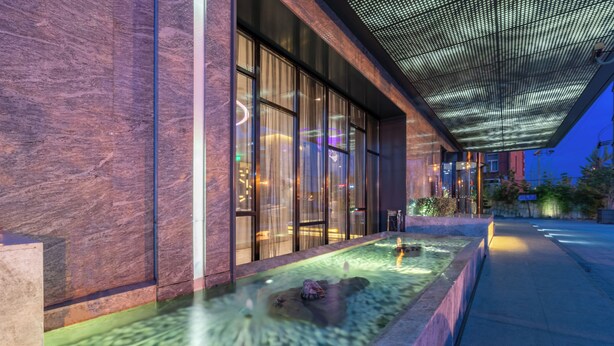 A modern building with large windows, a water feature, and a covered walkway. - Crystal Hotel Shanghai Intl. Tourism (Shanghai)
