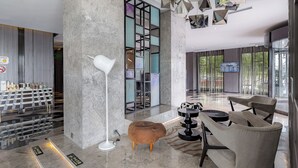 A modern lobby with a marble floor, a white floor lamp, a seating area with a sofa and chairs, and a large screen on the wall. - Crystal Hotel Shanghai Intl. Tourism (Shanghai)