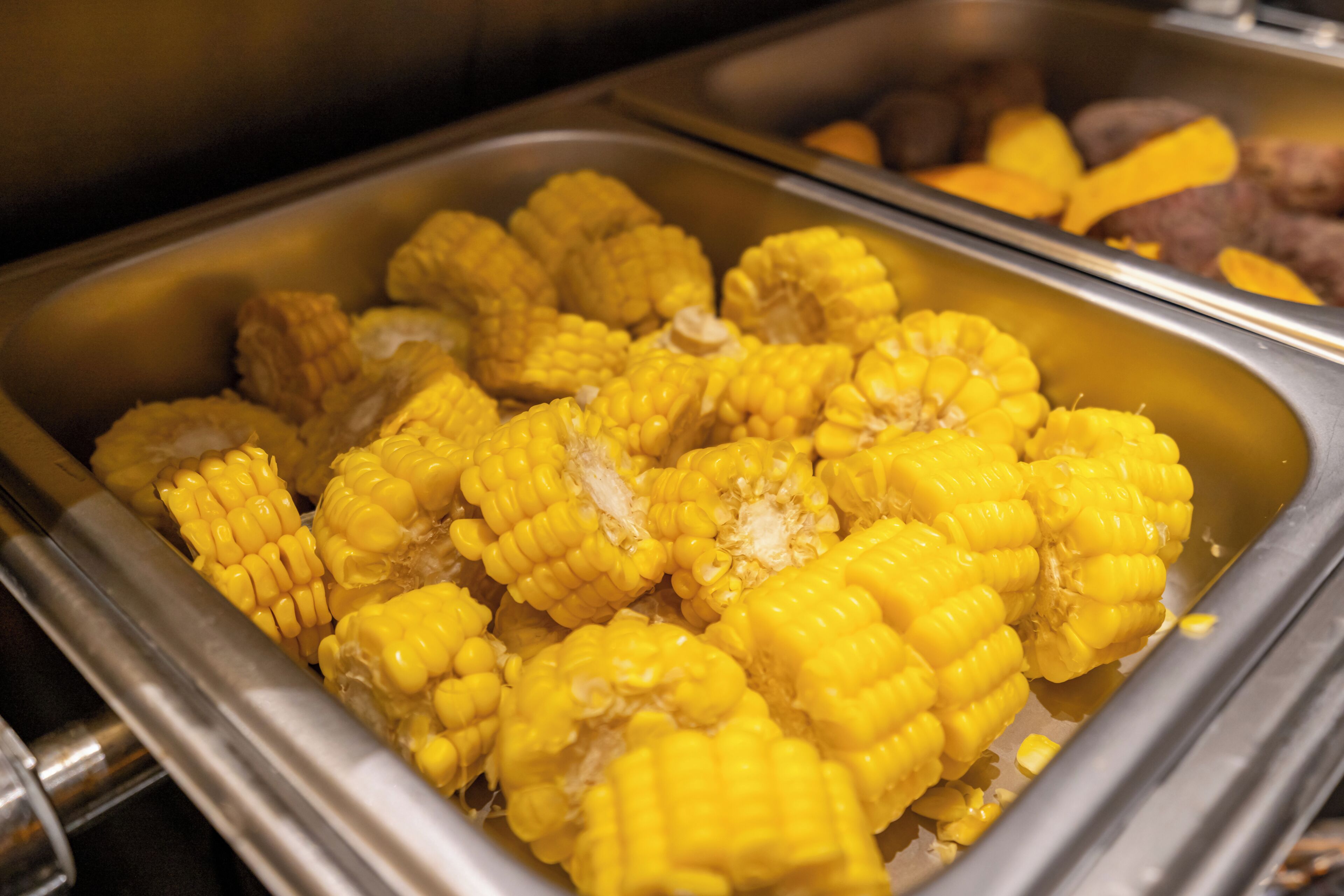 Un bufé con diversos alimentos, incluyendo maíz y papas.